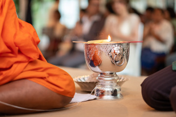 Buddhist monks doing the holy water ceremony with candle at thai wedding