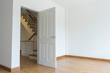 Empty room with white walls, open door and access to the staircase.