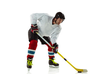 Activity. Young male hockey player with the stick on ice court and white background. Sportsman wearing equipment and helmet practicing. Concept of sport, healthy lifestyle, motion, movement, action.