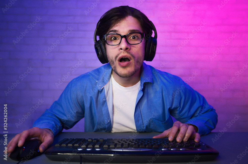 Poster amazed guy playing computer game online sitting at home