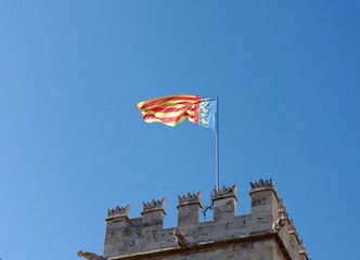 Flag of Valencia on top of Silk House. Daylight, clear blue sky. Old center of Valencia, Spain