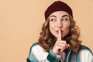 Photo of pretty joyful woman making silence gesture and smiling
