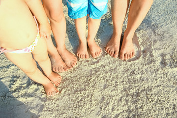 beautiful family legs on the sand by the sea