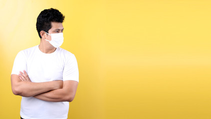 Asian man wearing a mask is sick Pointing finger isolated on yellow background in studio With copy space.
