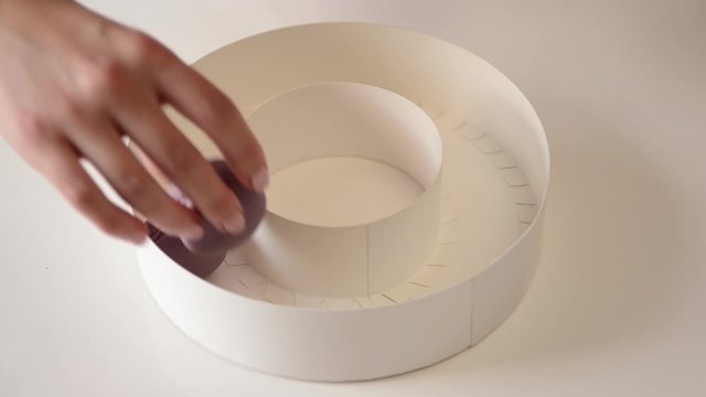 Woman's hand putting french macaroons in white gift box. Sweet colorful blueberry macaroons in gift box. Patisserie shop. Modern gift box with sweet macaroons.