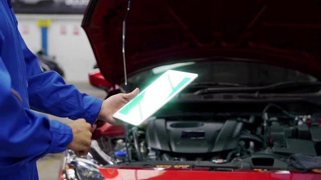 Professional auto mechanic using tablet pc while checking for car parts,Futuristic Technology Concept.
