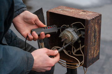 Using a universal voltage probe. Checking voltage at batch switch. Work electrician at the factory.