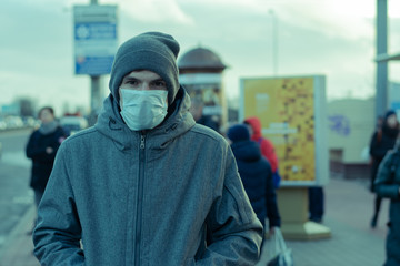 man in the city. on the face a protective rag mask. remedy against viruses and diseases. protection against coronovirus. Poisonous green tinted. there are a lot of passers-by around the street