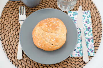 Plate with fresh crusty bread and glass of juice on grey plate