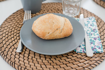 Plate with fresh crusty bread and glass of juice on grey plate