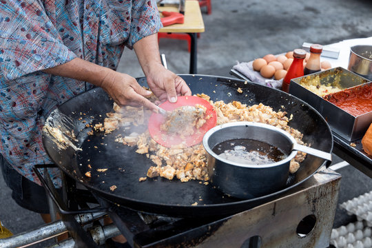 Malaysian hawker cooking frying radish carrot cake with egg in wok