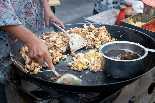 Malaysian hawker cooking frying radish carrot cake with egg in wok