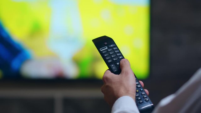 Back view of businessman using tv remote control