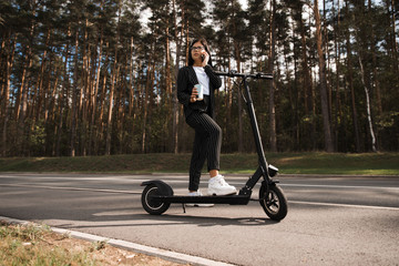 Business woman riding electric scooter at parking lot - Emission free eco friendly transportation