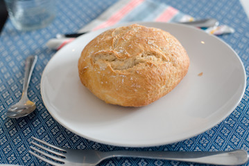 Plate with fresh crusty bread and glass of juice on white plate