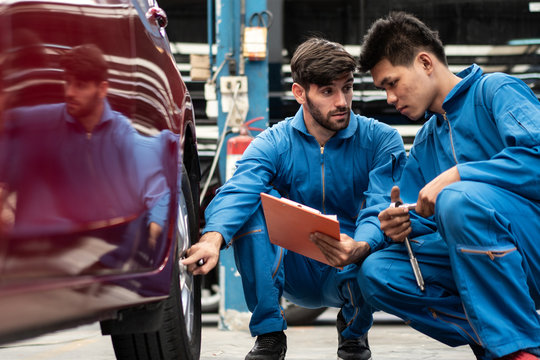 automotive mechanic men checking at  car tyre rubber condition needed for replacement, man pointing hand at wheel following maintenance checklist document, after service at auto repair shop concept