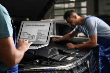 Fototapeta na wymiar Mechanic with laptop doing car diagnostic at automobile repair shop, closeup