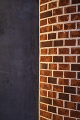 One part of the wall is red brick, semicircular, and the other smooth, painted black. Background.