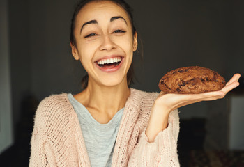 funny portrait of happy smiling woman posing with big chocolate cookie, laughing and looking at the camera. food, sweets and bakery concept.