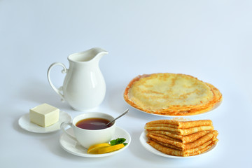 Pancake week: thin pancakes with butter and tea on white table.french crepes .thin pancakes and glass of milk on the table.Delicious breakfast.Selective focus