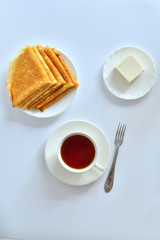 Pancake week: thin pancakes with butter and tea on white table.french crepes .thin pancakes and glass of milk on the table.Delicious breakfast.Selective focus