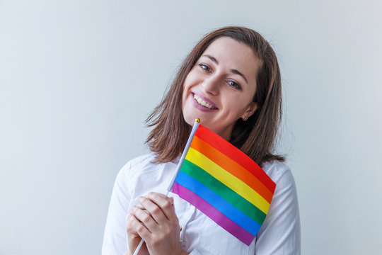 Beautiful caucasian lesbian girl with LGBT rainbow flag isolated on white background looking happy and excited. Young woman Gay Pride portrait. Equal rights for lgbtq community concept.