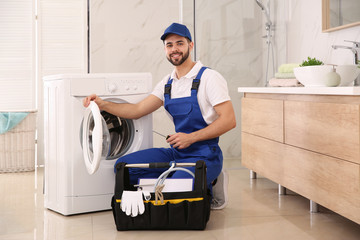 Repairman with toolbox near washing machine in bathroom