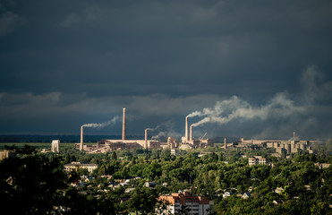 Fototapeta na wymiar View of an industrial facility located in a residential area with many smoking chimneys. Ecological problems of environmental pollution