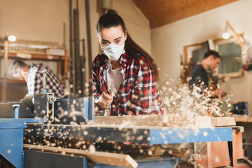 Female carpenter cleaning surface planer with air blow gun in workshop