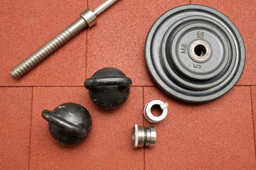 Obraz na płótnie Canvas Dumbbells and kettlebells on a floor. Bodybuilding equipment. Fitness or bodybuilding concept background. Photograph taken from above, top view