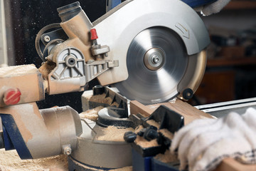 Professional carpenter cutting wooden planks with sawmill in workshop, closeup