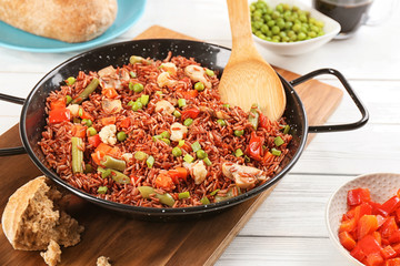 Tasty brown rice with vegetables on white wooden table