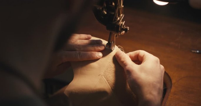 Traditional bespoke shoemaker stitching sewing leather upper old sewing machine over the shoulder