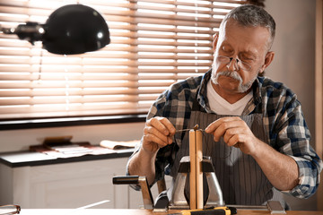 Man sewing piece of leather in workshop