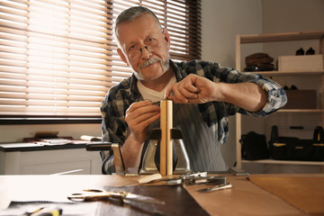 Man sewing piece of leather in workshop