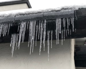 Close up view of group of icicles hanging on the side of a building.