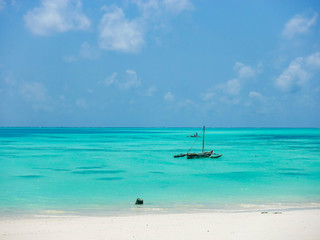 Wooden African boat in the beautiful azure waters of the ocean near the coast of a tropical island with white sand