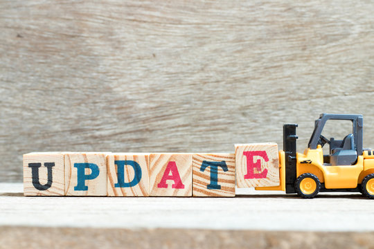 Toy forklift hold letter block e to complete word update on wood background