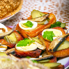 Sandwiches with smoked sprats, boiled egg, pickles and parsley on a plate