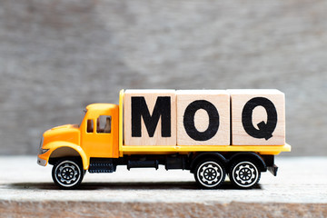 Truck hold letter block in word MOQ (Abbreviation of Minimum Order Quantity) on wood background