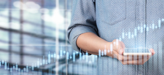 Fototapeta premium Hand holding smartphone device and touching screen. Stock exchange market concept