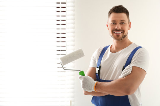 Man holding paint roller near window indoors. Space for text
