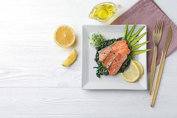 Tasty salmon with spinach served on white wooden table, flat lay