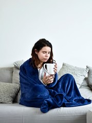 The young girl drinks tea on mit royal blue warm blanket