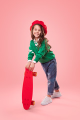 Trendy girl with skateboard smiling for camera