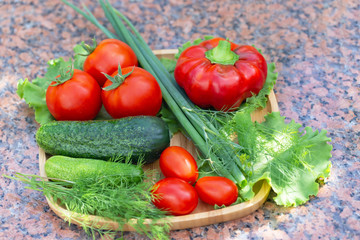 Still life of fresh vegetables on a granite background. A set of tomatoes, red pepper, cucumbers, green onions, lettuce and dill. The concept of healthy, vitamin food.