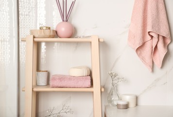 Shelving unit with towel and decorative elements in bathroom interior