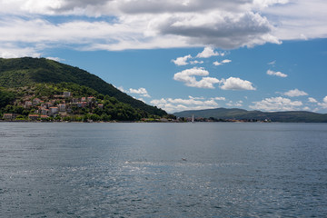 Landscape of mountains, sea and the small towns in the Boka Kotor bay of the Mediterranean Sea sunny day and white clouds. Montenegro.