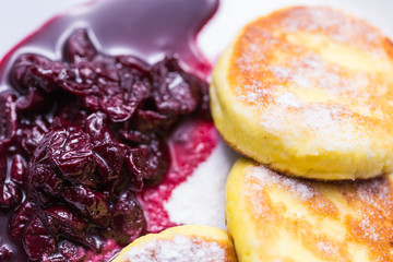 Cottage cheese pancakes with cherry jam, close up, top view.