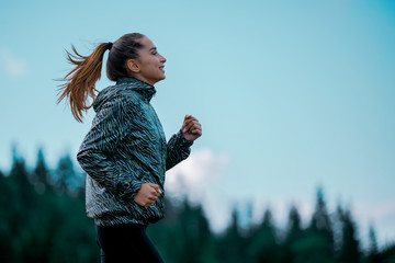 young fitness woman running at forest trail - 324283086